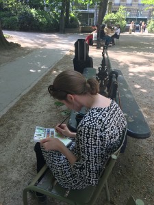 young woman sitting on bench painting in Jardin de Luxembourg