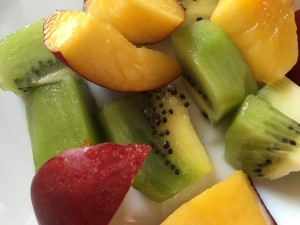 close up photo of cut up kiwi and nectarine in white bowl