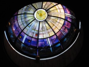 Photo of a domed stained glass window In Church in Rome, Italy, depicting the universe.