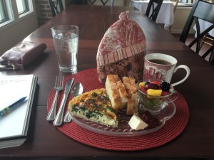 Breakfast of quiche, toast, cup of fruit, and butter and jam.