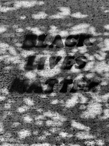 close up of stenciled words on sidewalk "Black Lives Matter"